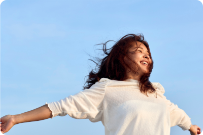 Frau genießt die Sonne im Freien, Sonnenstrahlen im Gesicht – Vitamin-D-Produktion durch Sonnenlicht.