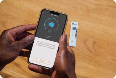 Person scannt zuhause Testkassette zur Darmkrebsvorsorge mit iPhone und erhält Zahlenwert