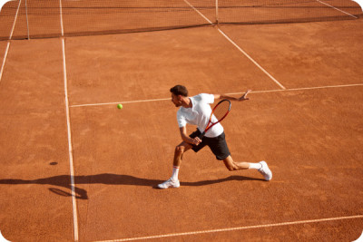 Junger Mann, Tennisspieler, zeigt Ausdauer und Kraft waehrend intensivem Training auf Sportplatz.