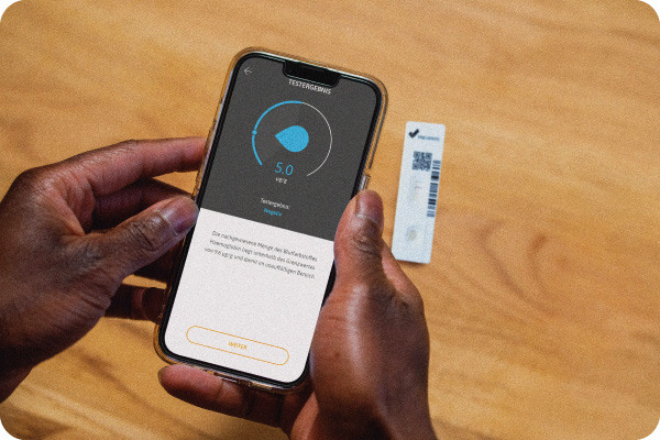 Eine Person fuehrt zu Hause mithilfe eines iPhones einen Stuhltest zur Darmkrebsvorsorge durch und erhaelt einen numerischen Wert.