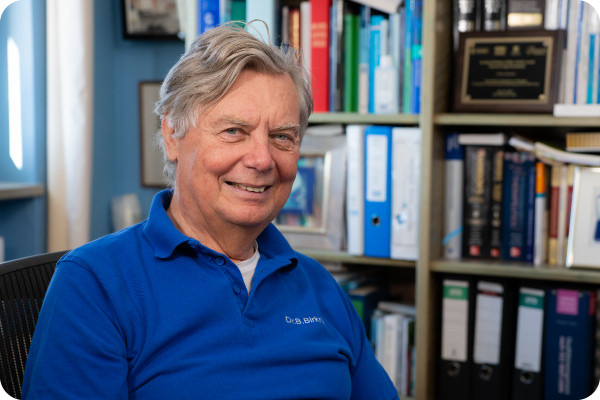 Doctor Birkner, a gastroenterologist and president of the Network Against Colorectal Cancer, sits at his desk, smiling.