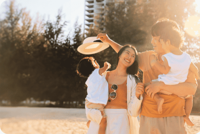 Eine Familie mit zwei kleinen Kindern genießt die Sonne im Sommerurlaub am Strand, um Vitamin D zu tanken.